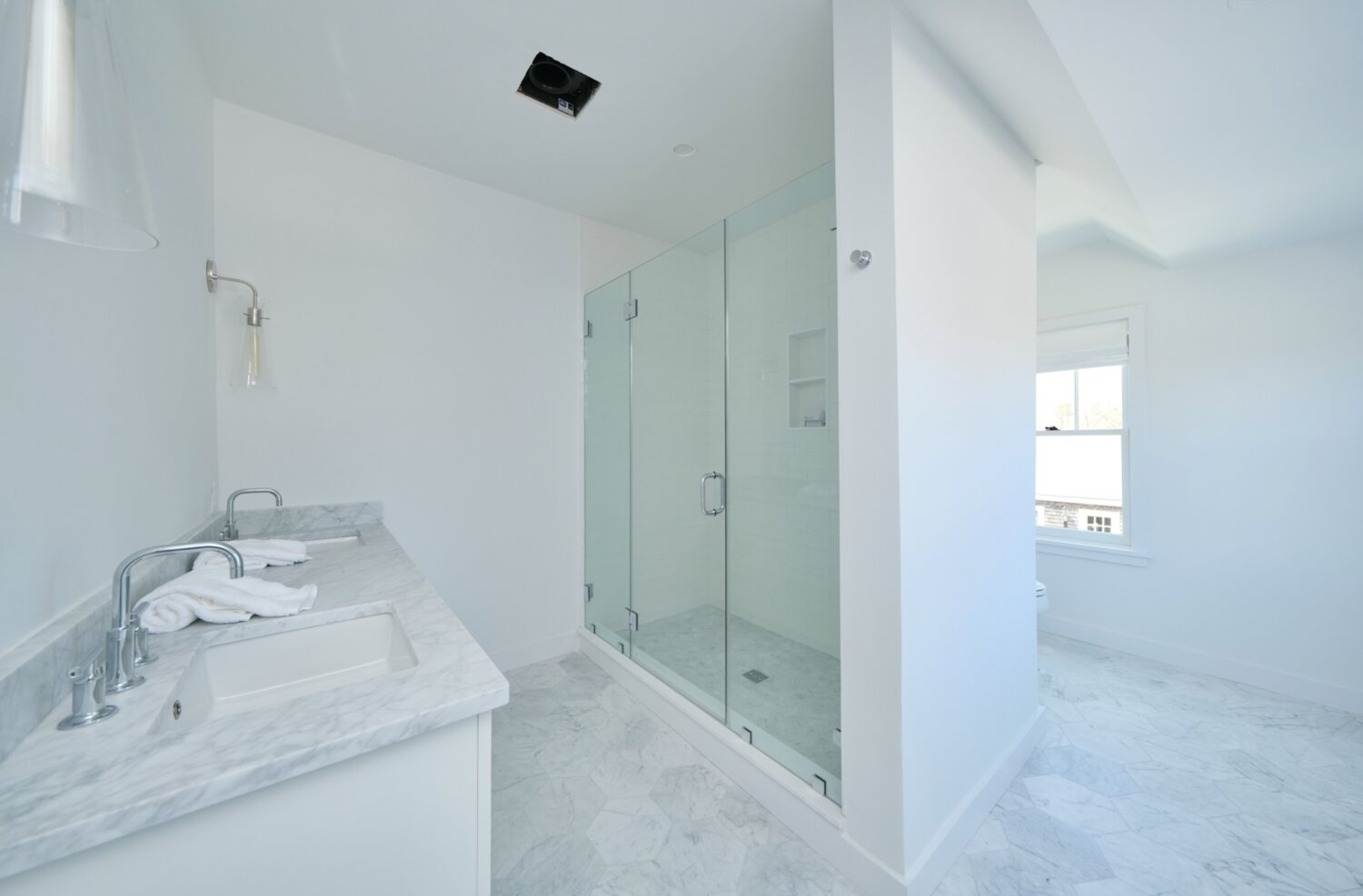 The master bath has a glass shower and dual vanities.