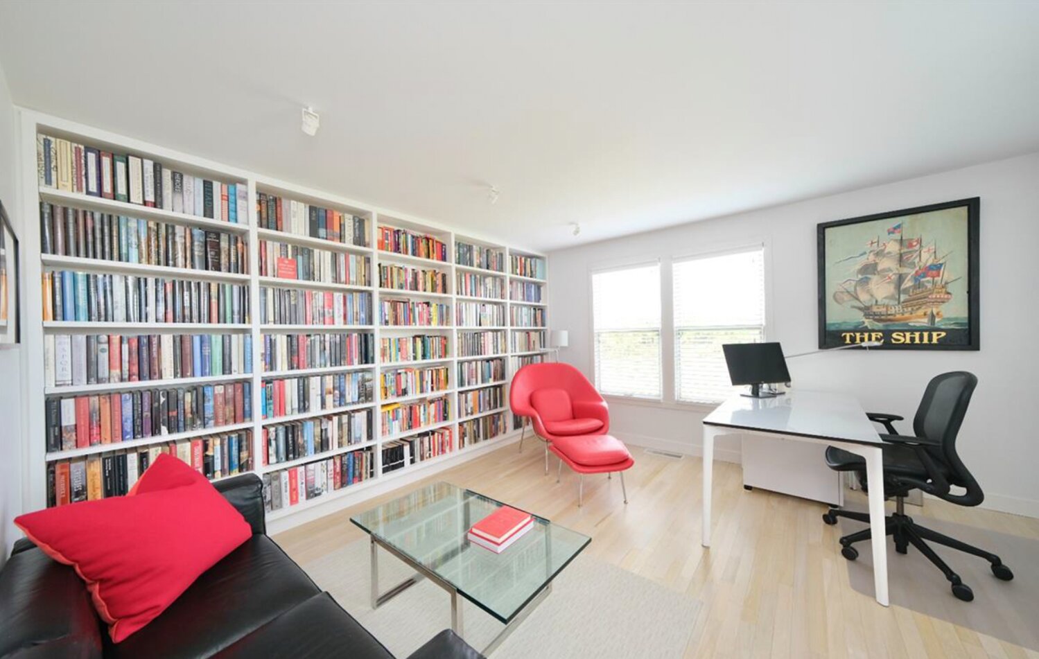 The den/office has a wall of built-in bookshelves, light wood floors and plenty of space to relax or work.