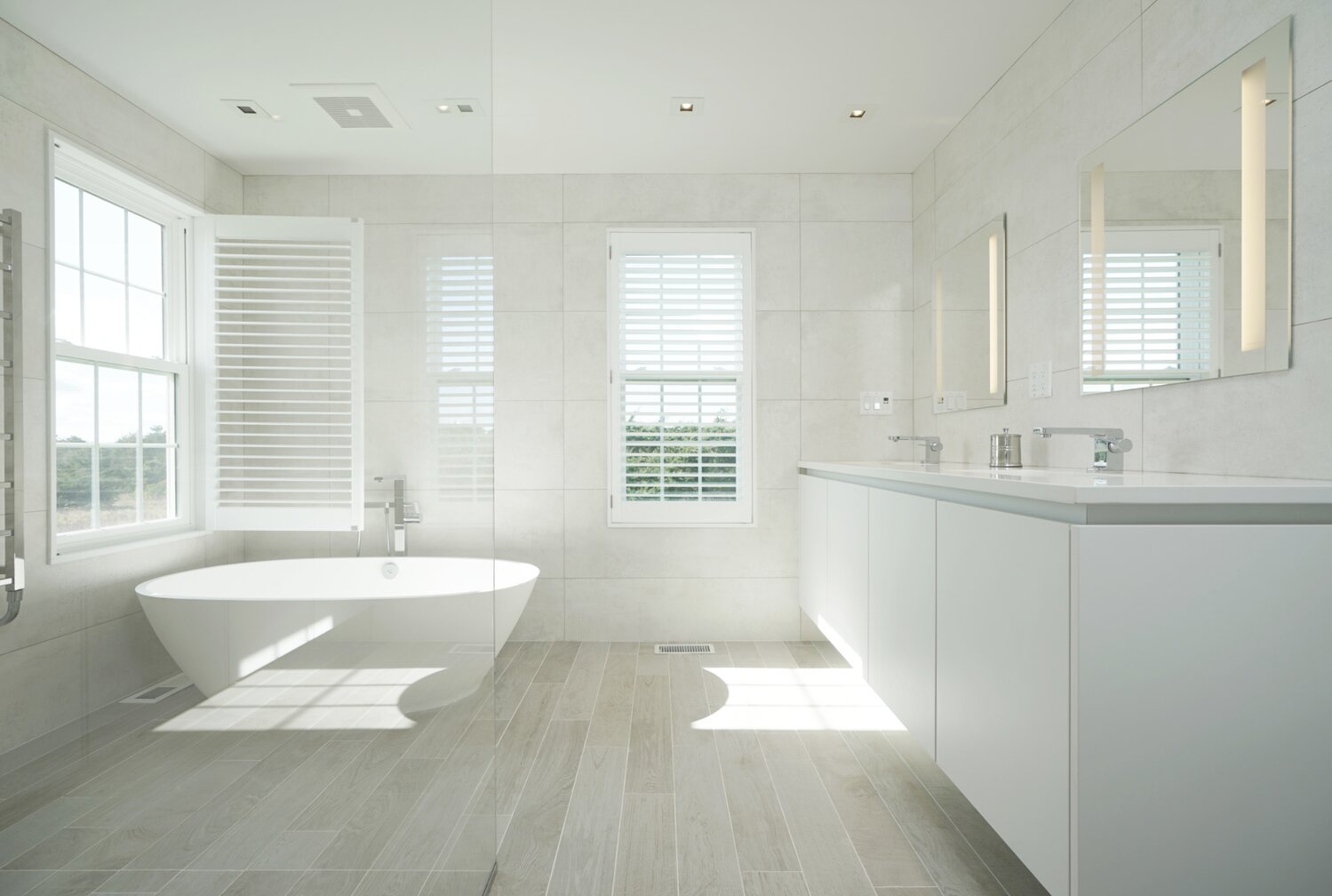 This bathroom has dual vanities, a soaking tub, glass-enclosed shower and plenty of natural light.