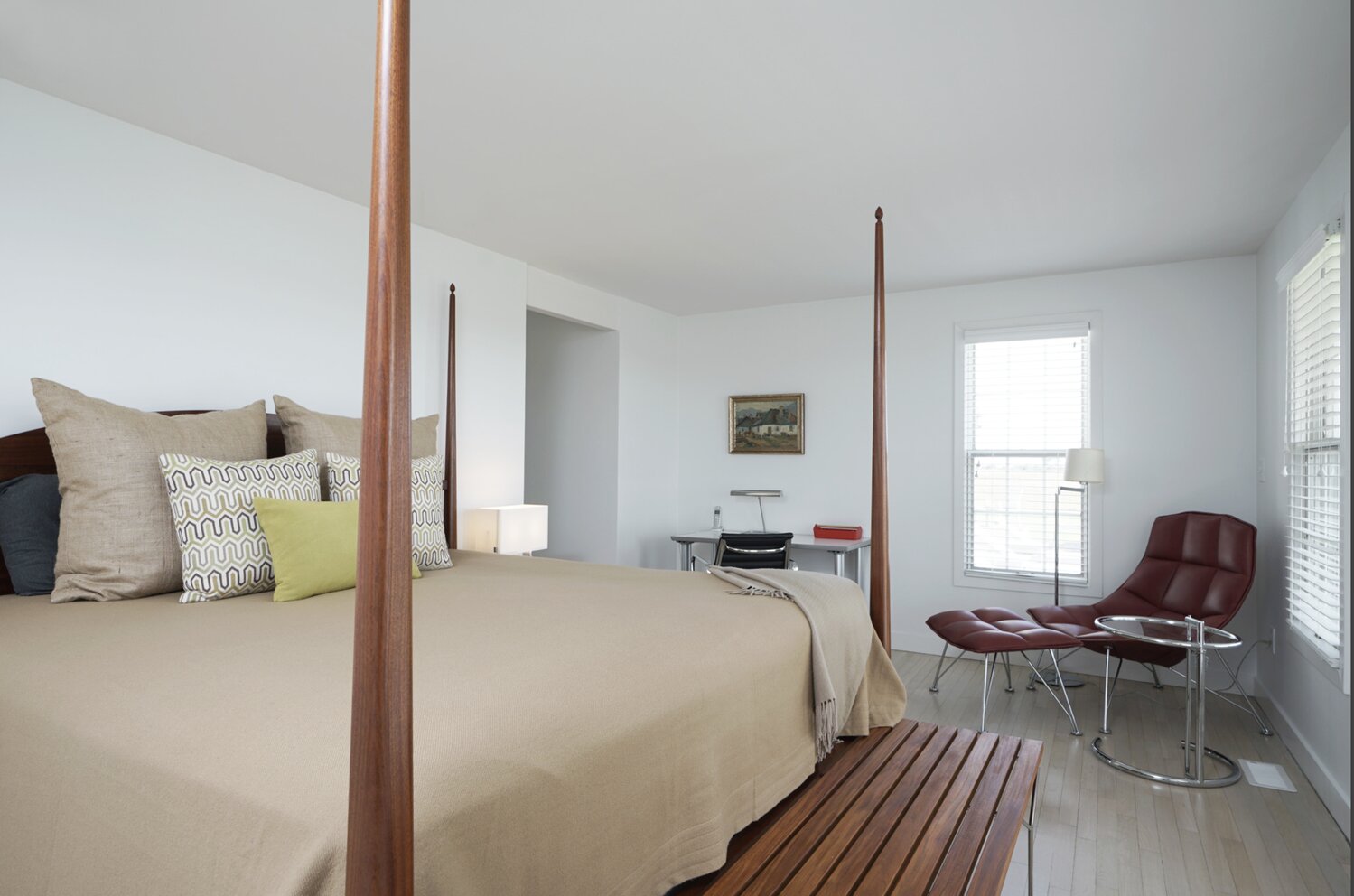 This second-floor bedroom has wood floors and enough space for a sitting area and small workspace.