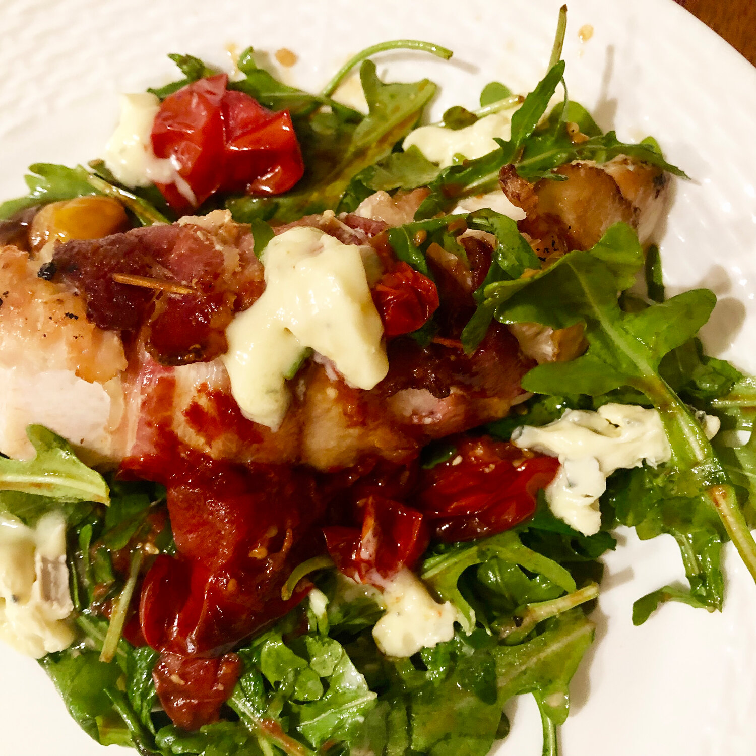 Bacon wrapped chicken with blue cheese and blistered cherry tomatoes.