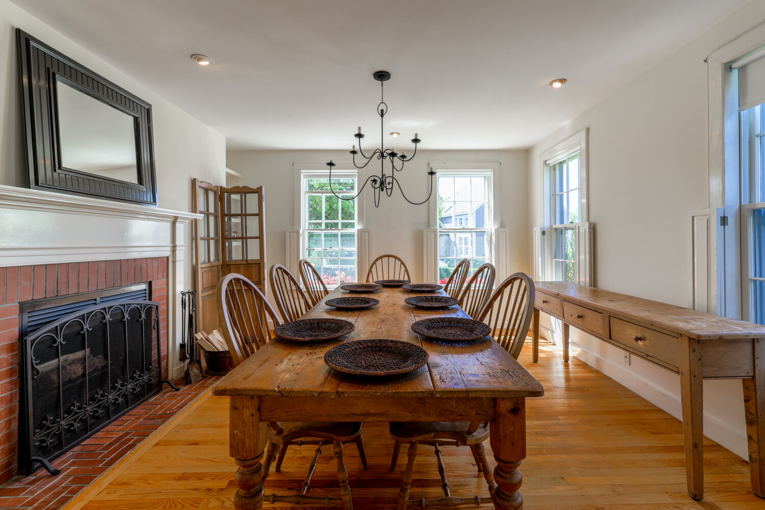 The dining room has wood floors, a wood-manteled fireplace surrounded by red brick, and overlooks the front yard.