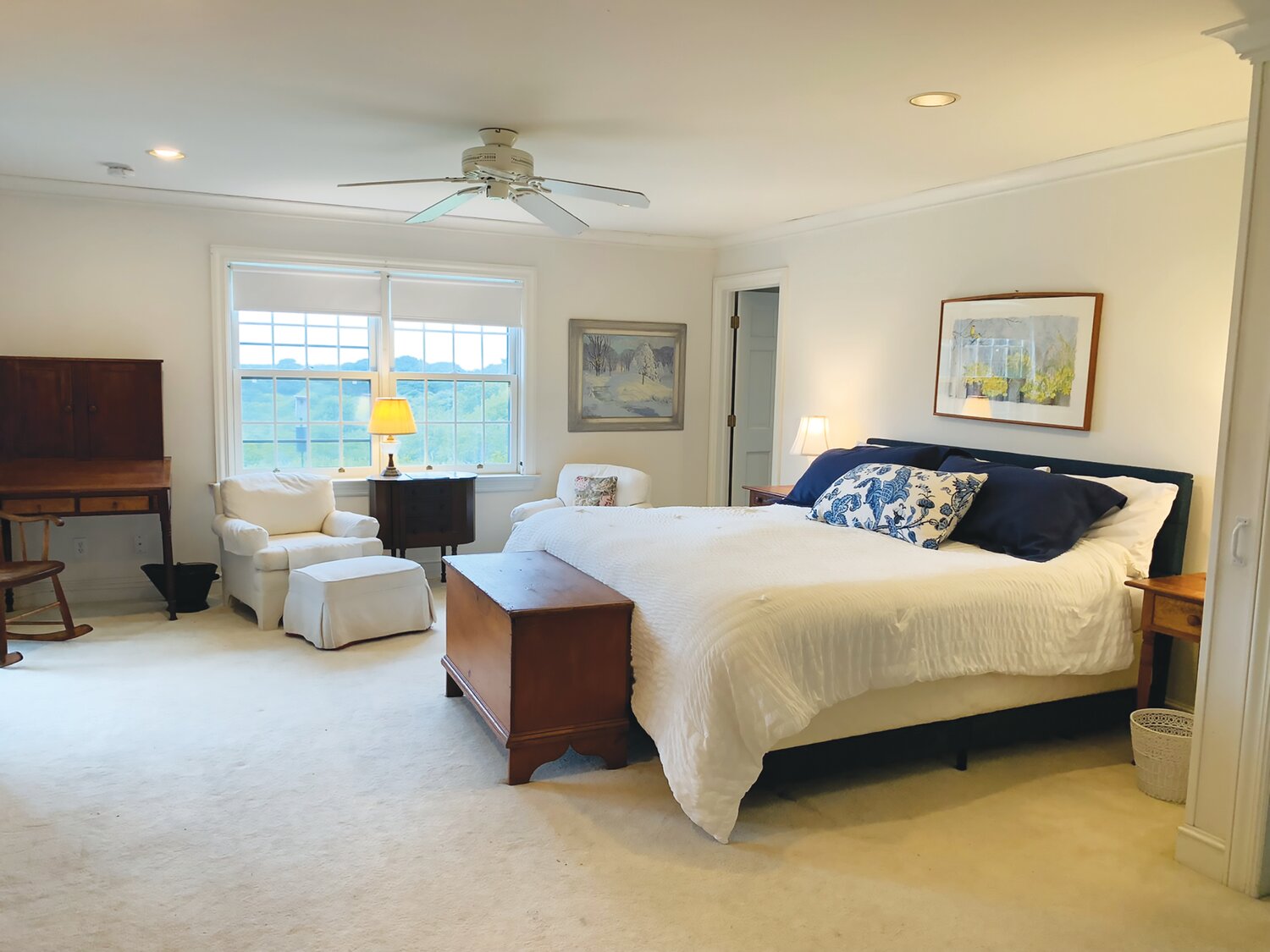 This carpeted bedroom in the main house has a ceiling fan and recessed lighting.