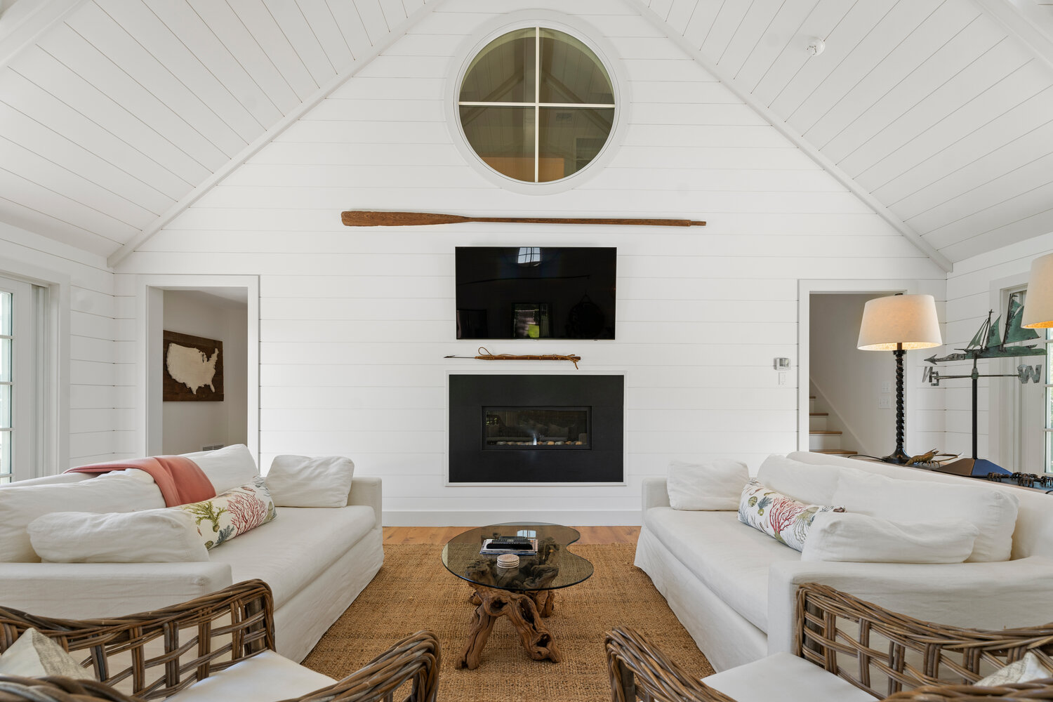 The guest house living room has a vaulted ceiling, shiplap walls and a gas fireplace.