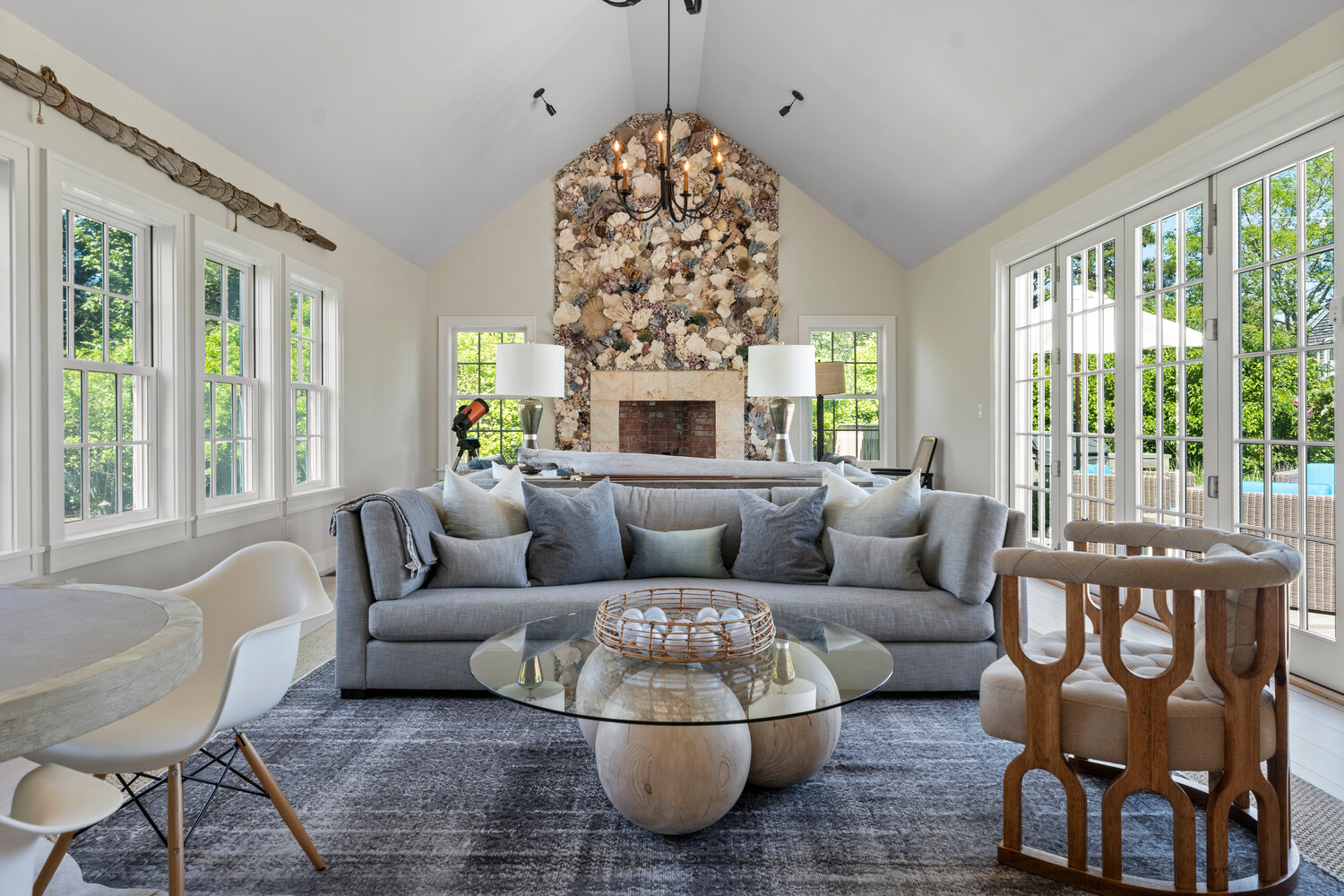 The living room has a vaulted ceiling, multiple windows and a dramatic fireplace with a floor-to-ceiling shell surround.