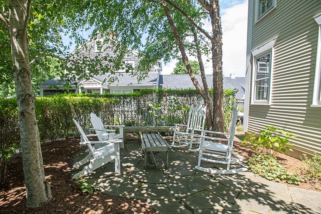 This cozy sitting area surrounded by mature hedges is located just off the patio.