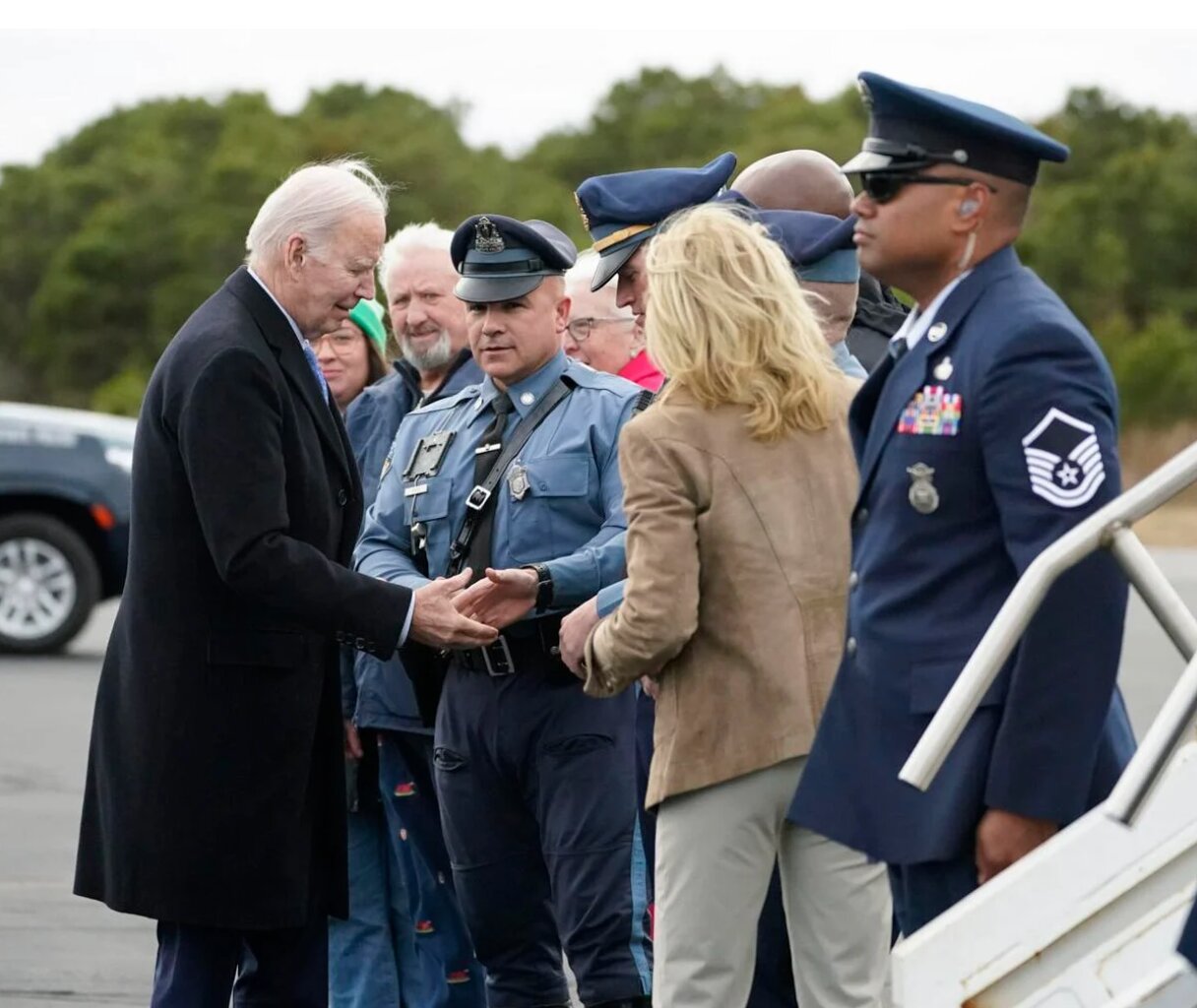 The president and first lady greet State Troopers on the tarmac at Nantucket Memorial Airport before leaving the island Sunday. At rear are Faregrounds Restaurant owners Bill and Kim Puder.