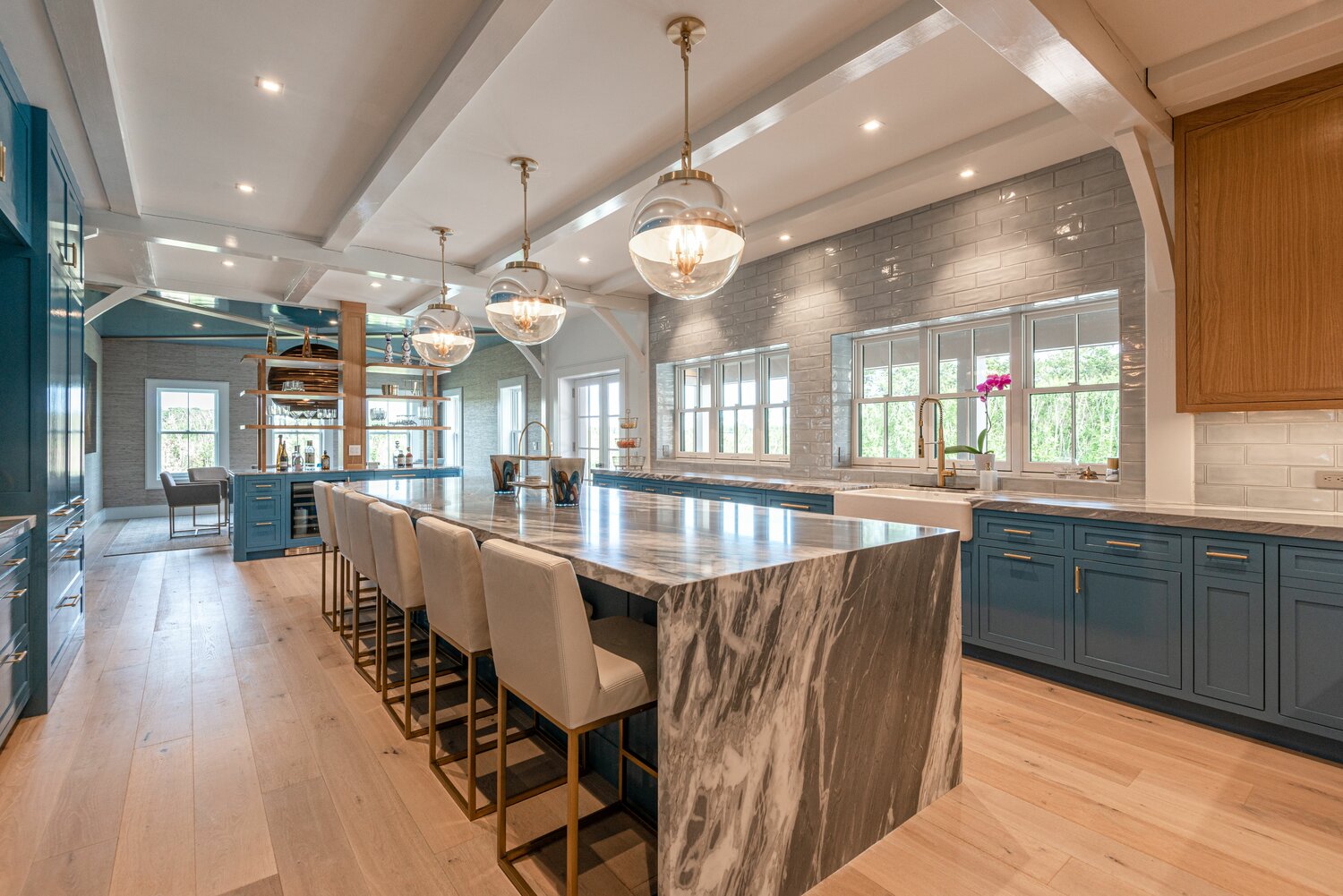 The spacious gourmet kitchen has an abundance of counter space and storage, high-end appliances and a bar area with wine chiller and exposed shelves.