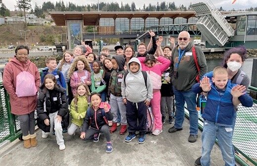 Third graders and teachers from Columbia Elementary School pose for a photo while on the sun deck of a ferry while docked at Mukilteo terminal.
