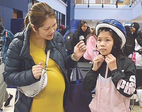 Tristine Vu (right), a Lake Stickney Elementary fifth grader, tries on a bicycle helmet with mother Tammy Nguyen at the Mukilteo Police table during the Mukilteo School District’s annual Back-to-School Fair Friday at Mariner High School;