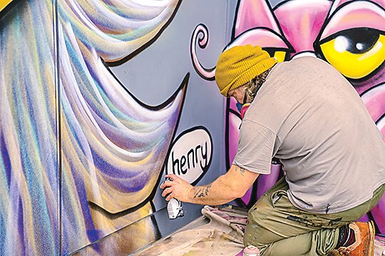 Henry’s Sasquatch works his Sasquatch mural at Brigid’s Bottleshop. (Photo courtesy Amanda Thornton-DeWitt)