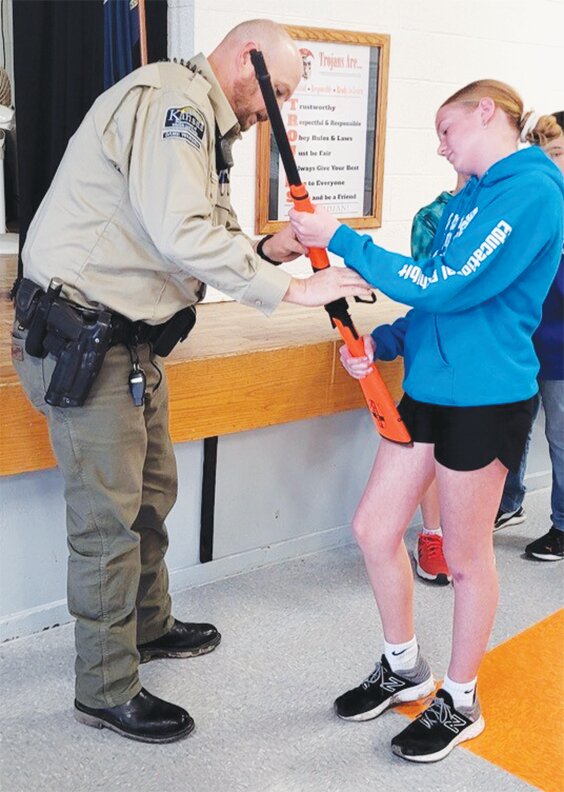 Kansas Wildlife & Parks Game Warden, Landen Cleveland, talks about lever action steps with Beloit Grade 6th grade student, Aspen Thiessen. 