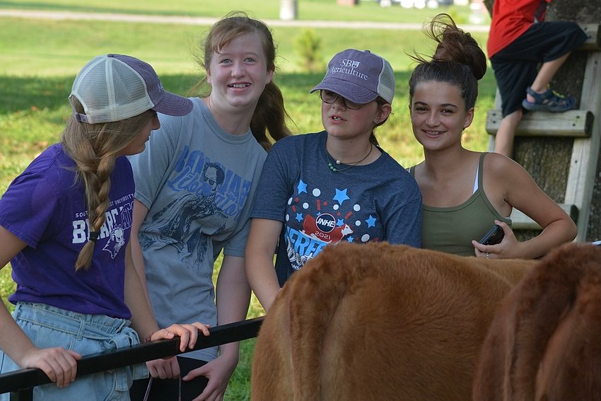 Elle Johnson, Jaylee Bryant, Emma Hancock and Isabella Arcadipane support Hancock Farm&rsquo;s booth by chatting near two of the farm&rsquo;s heifers.&nbsp;&nbsp;