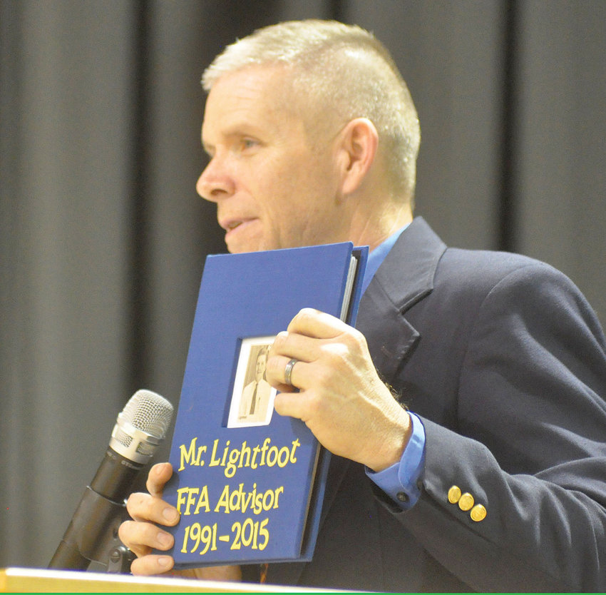 Pictured here in 2015 as he transitioned to high school principal, after 23 years as Fair Play&rsquo;s FFA adviser and ag instructor, Randy Lightfoot holds up a book of memories his former students compiled . The front of the book includes a photo of Lightfoot that appeared in the July 22, 1992, edition of the Bolivar Herald-Free Press. Lightfoot said the photo was taken the day he was hired.&nbsp;