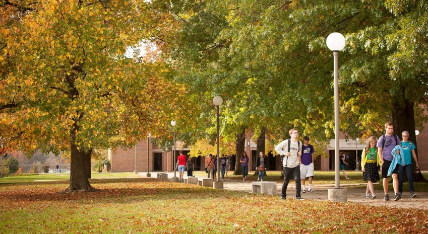SBU students walk across a campus highlighted by fall colors.