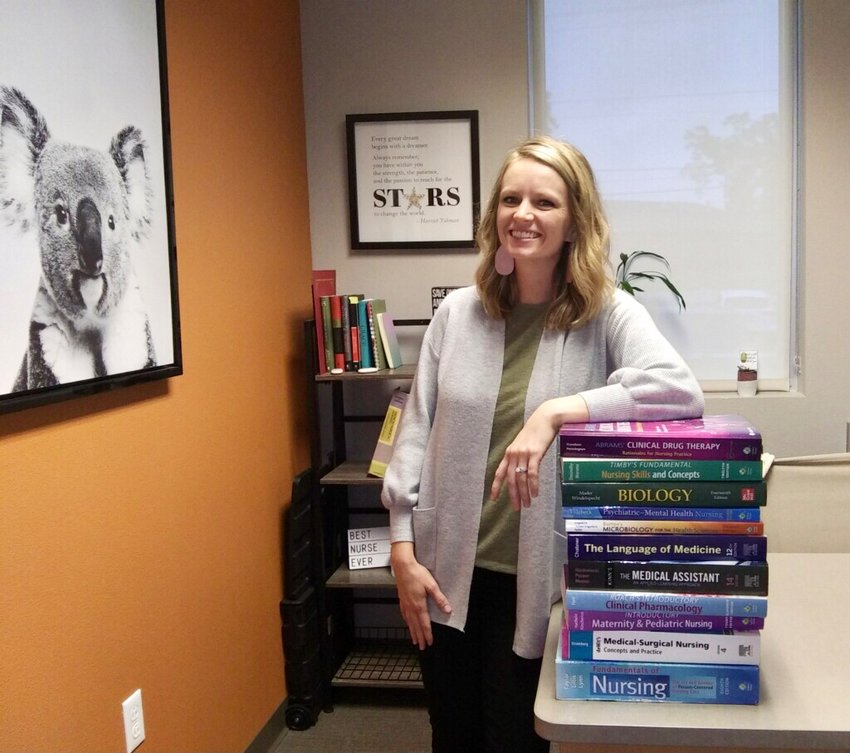 Kayla Hendricks, Assistant Director of Nursing Education, stands next to textbooks BTC students currently purchase. Starting in January, students can rent textbooks using Slingshot.