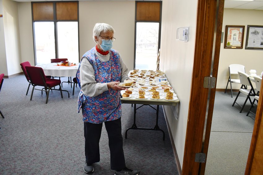 Volunteer Bette Thompson prepares to serve an attendee some dessert from a well-stocked table.