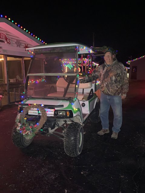 Mike Wood stands beside the golf cart he uses to pull a train car through his light display, east of Bolivar on Mo. 32.