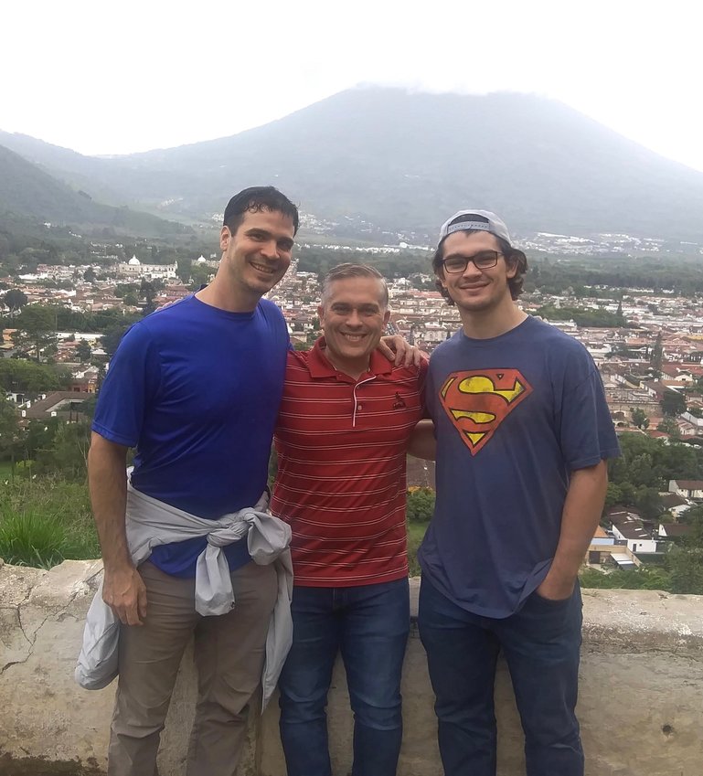 Pictured from left, Danny Stimpson, Matt Bunn, and Andrew Bunn stand in front of the city of Antigua, Guatemala with a volcano looming in the distance.