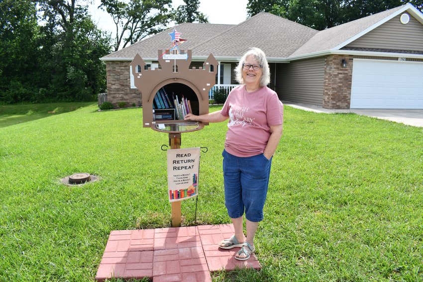Laurel Benson stands in front of the Camelot Little Free Library outside her home at 1260 North Chicago Avenue in Bolivar.