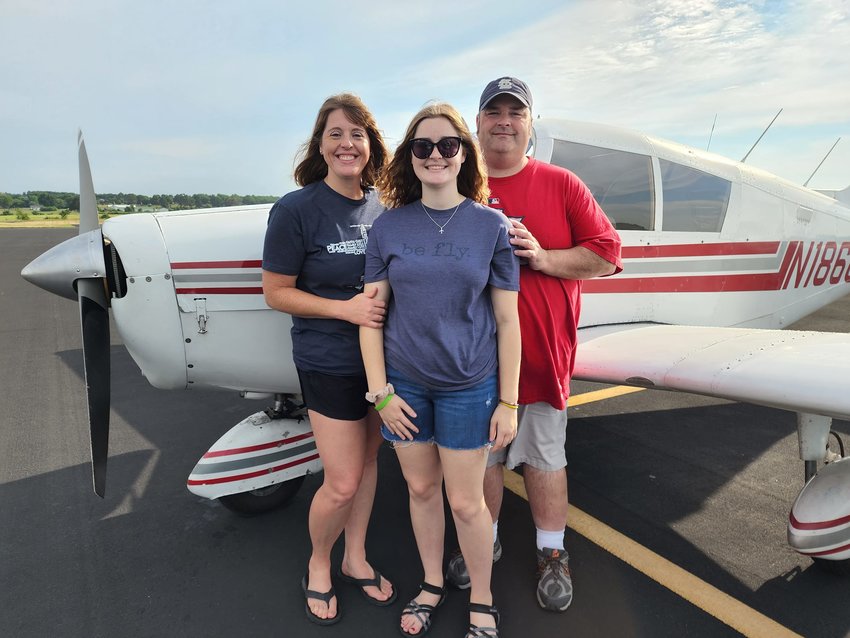 After a ride in the skies, Kelsey stands in front of her plane with her parents, Joy and David.