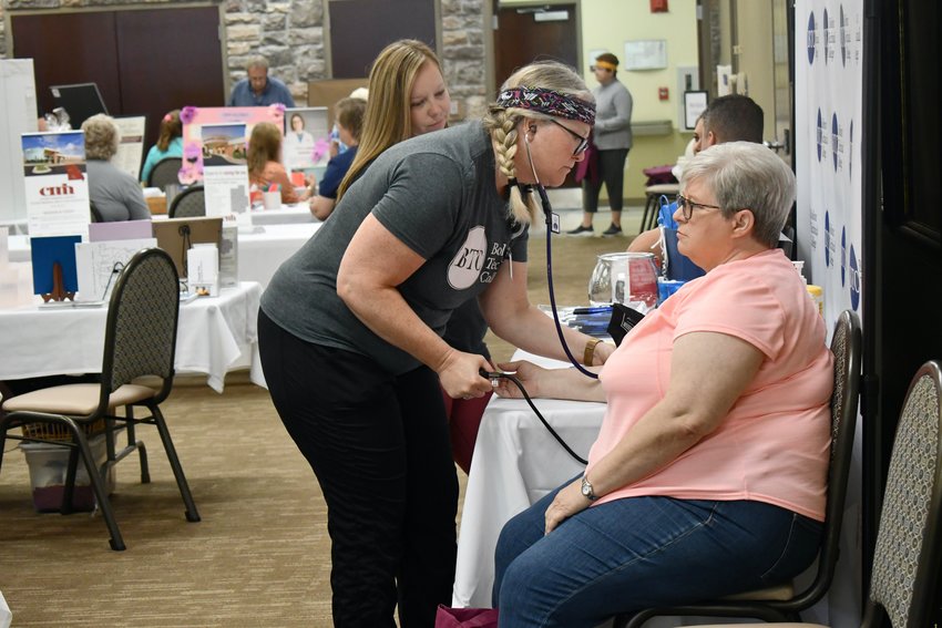 Erin Mock gets blood pressure from an attendee while Courtney Sulltrop observes. Mock and Sulltrop are both faculty members at Bolivar Technical College.