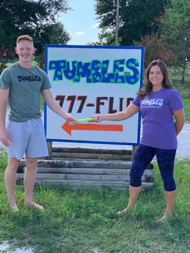 Celebrating his title as the new owner of Tumbles, Gage Foster (left) receives the ceremonial baton from current owner, Crystal Hensley (right).