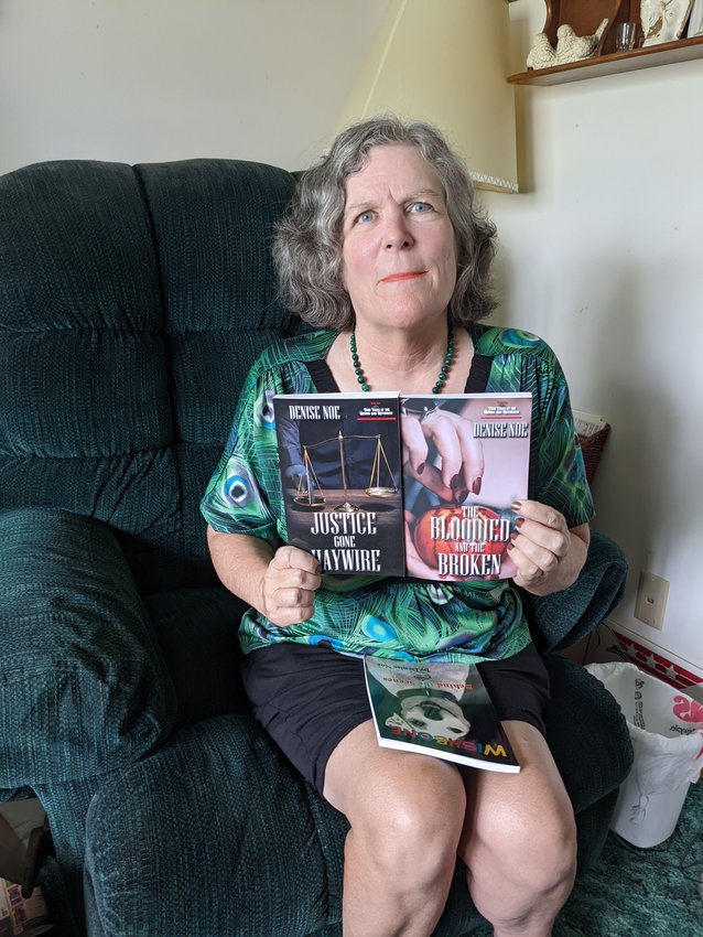 Local author Denise Noe with her true crime books Justice Gone Haywire and The Bloodied and the Broken