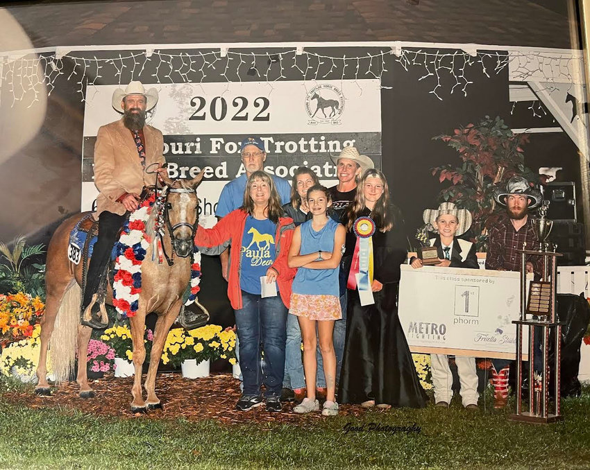 Vance Vahle shares the limelight with horse Paula Deen after winning the MFTHBA World Grand Championship. Others included in the photo: Bottom row (left to right): Barb Palmer, Jacey Revey, and a MFTHBA ribbon presenter. Top row (left to right): Ricky Palmer, Jessica Revey, and Jody Vahle.