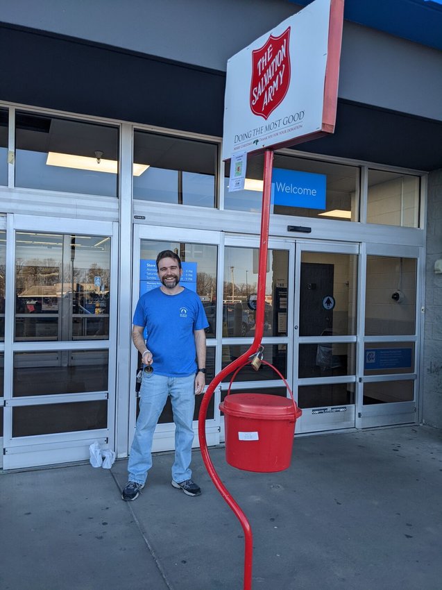 Zach McIntire, pastor of Living Faith Fellowship, gives a cheery greeting to Walmart customers as he rings the bell for the the Red Kettle Campaign and waits for the rest of his group to join him for Christmas carols.