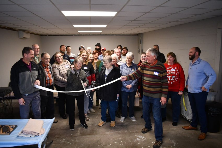 Friday, Dec. 2, the Warming Center hosted an open house and ribbon cutting with the Bolivar Area Chamber of Commerce. Pictured cutting the ribbon is Karen Tweed, volunteer coordinator, while other members of the board and chamber look on. STAFF PHOTOs/LINDA SIMMONS