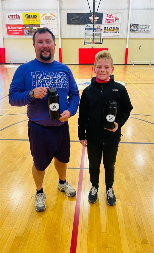 As the first place winners of their respective races, John Shikles, left, and Jackson Greer, right, display their prize-winning water bottles.