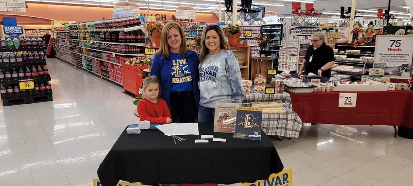 Bolivar Athletic Booster Club secretary Katie Adams (middle) recruits the help of her niece Elizabeth Stanley (left) and fellow booster club member Jennifer Carr (right) to raise funds at Woods Supermarket&rsquo;s 75th anniversary on Saturday, Nov. 12.