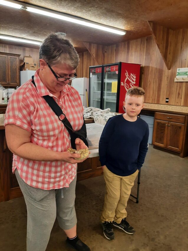 Velynda Cameron, a 4-H specialist at the MU Extension, takes a turn holding Sunni the snake, as Sunni&rsquo;s owner Mark Black looks on.