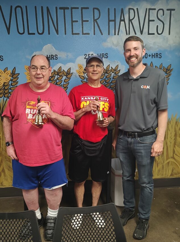 Steve Dunlap and Wayne Clark claim their bell ringing award after years of volunteerism. On the far right stands Micah Titterington, executive director of COM.