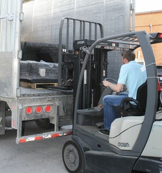 Micah Titterington, executive director of Community Outreach Ministries, unloads benches and tables from Champlin Tire Recycling, Inc. truck.