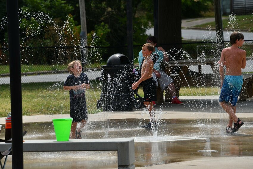 Kids cool down on a warm summer day at the Splash Pad after eating their free lunch.