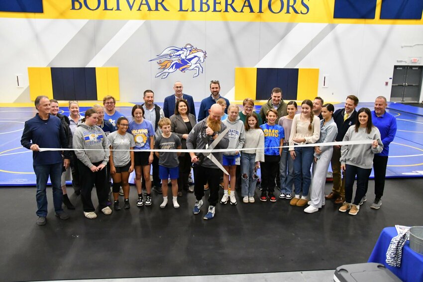 Liberator wrestling coach Clayton McCullah cuts the ribbon at the new FEMA gym on Monday, Oct. 30, surrounded by school board members, students and Chamber of Commerce members.   STAFF PHTOO/LINDA SIMMONS