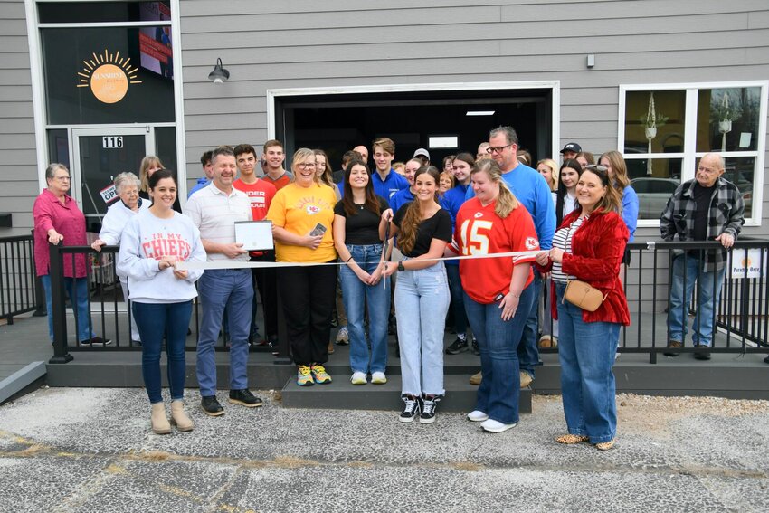 Surrounded by chamber members, friends and family, Mia Payne cuts the ribbon at her new business, Sunshine Bowls and Bakery.   STAFF PHOTO/LINDA SIMMONS