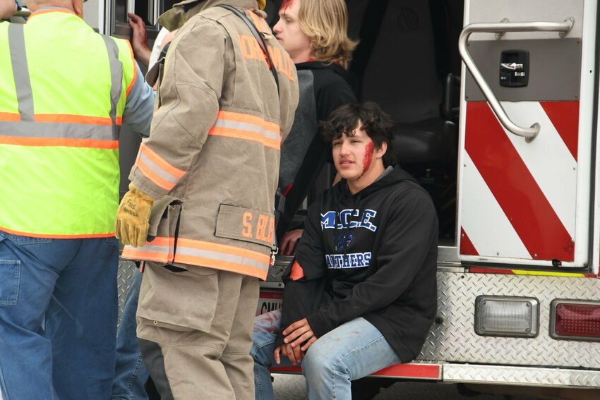 Student actor Landen Burrow appears dazed at the back of the ambulance as he watches first responders continue to work the simulated scene at the MCE docudrama.   STAFF PHOTO/ANNIE THOMAS