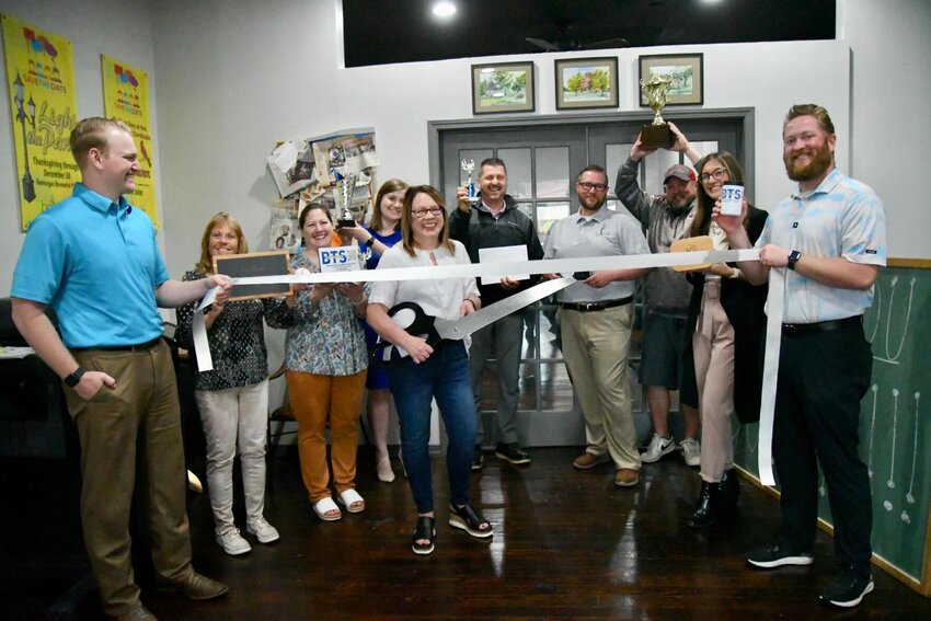 Tracy Hadank, owner of Brad&rsquo;s Trophy Shop, cuts the ribbon as chamber members, friends and family celebrate with her.