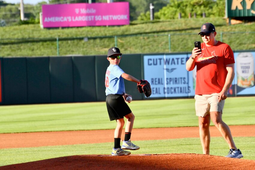 John Taylor, throwing out the first pitch, as dad Jared Taylor videos the excitement.   STAFF PHOTO/LINDA SIMMONS