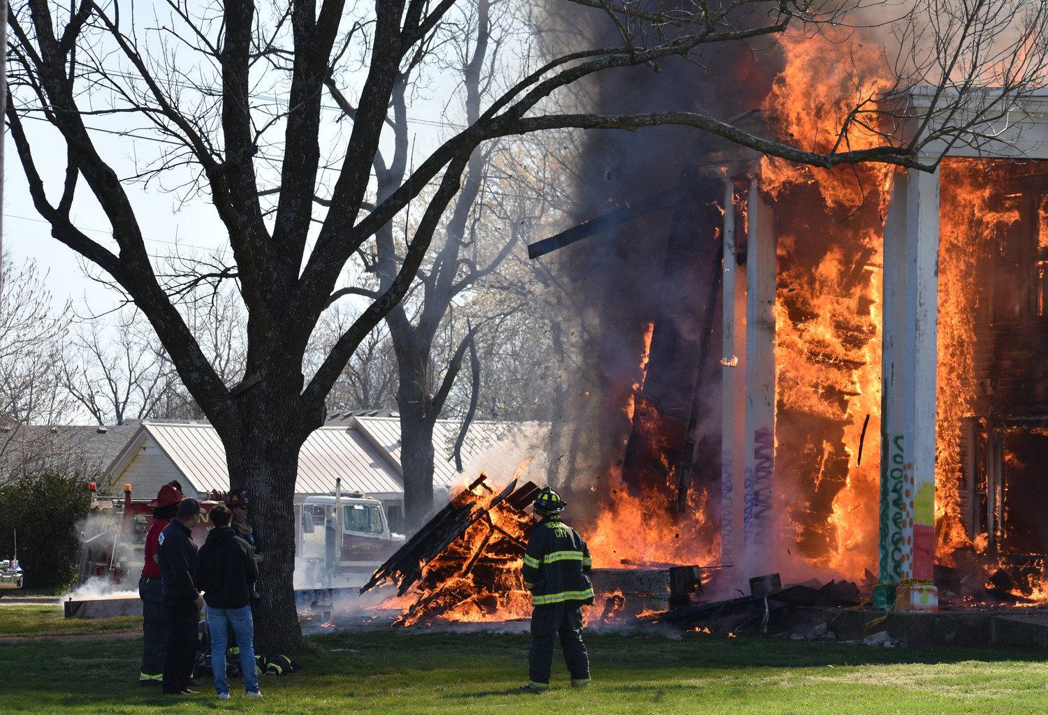 The firefighters look small compared to the backdrop of the burning house as they work the controlled burn Saturday, April 9.
