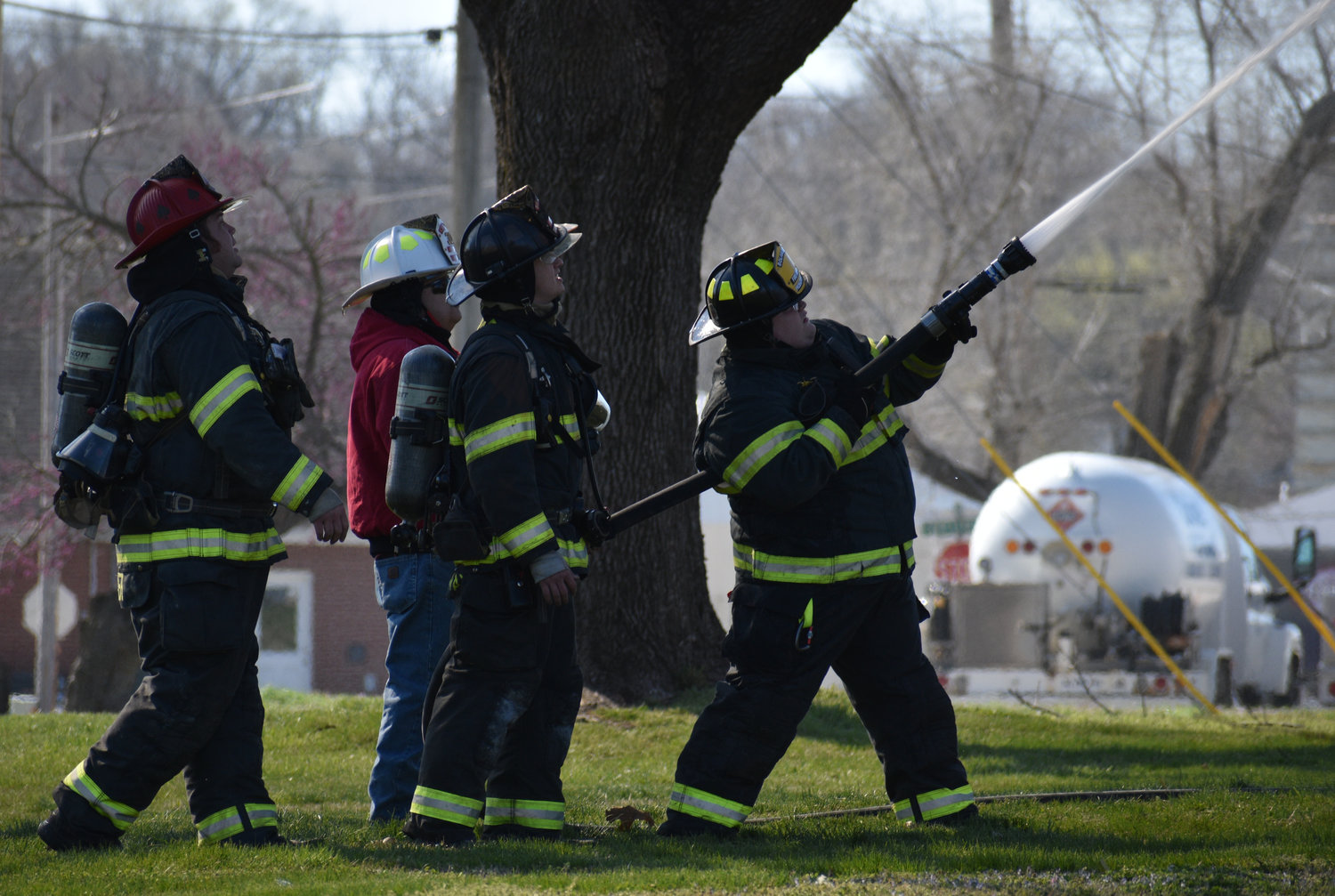 Standing in the house’s east lawn, Bolivar City firefighter Tommy Gerean, with the help of Bolivar Capt. Jeremiah Archer, Morrisville Fire Protection District Chief Ken Witt and Bolivar firefighter Caleb Dunaway, sprays water on the house to help control the fire.