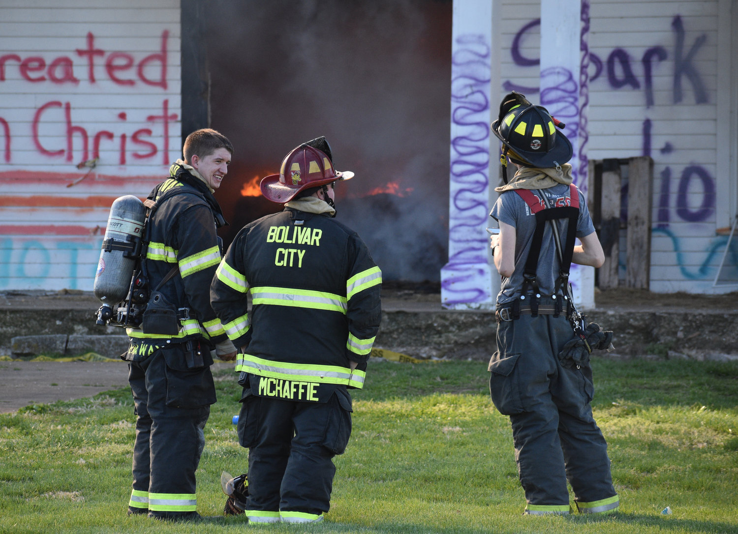 Firefighter Caleb Dunaway, Capt. Dustin McHaffie and firefighter firefighter TJ Elkins watch the fire from the house's front lawn.
