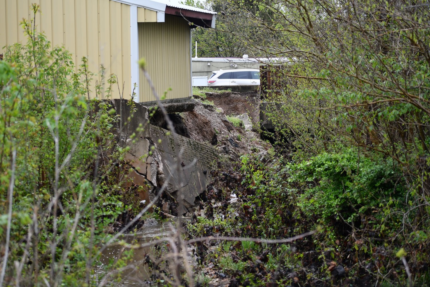 A close up view of concrete sliding down the embankment behind Sho-Me Muffler and Brake.