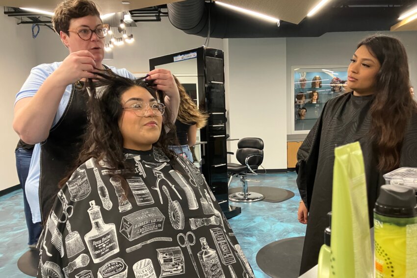 RL Turner High School graduate Kate Sultana shows Vania Silvestre and Leslie Torres how to make the most of Torres’ curls. (Photo by Kate Bergeron)