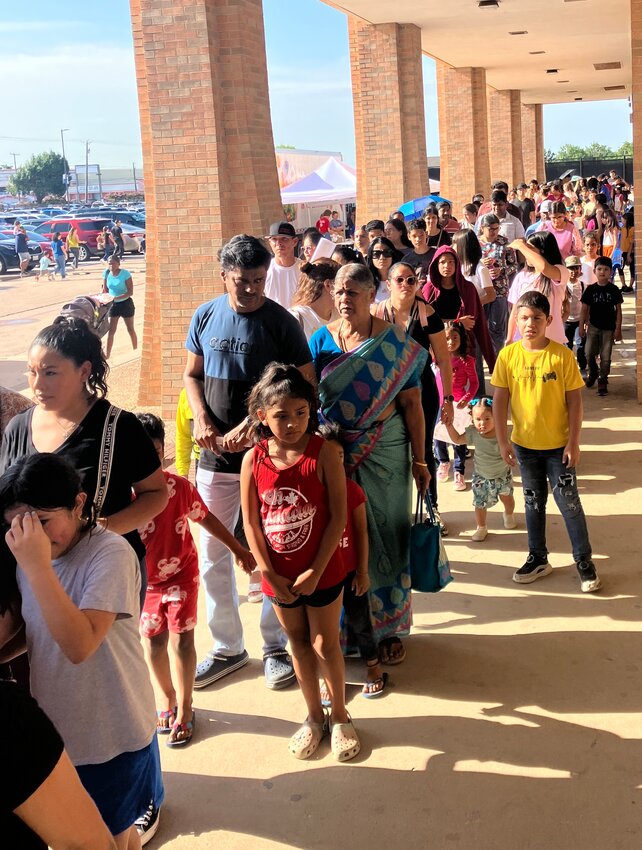 Families take their place in line while waiting to get into Back to School Fest at RL Turner High School.