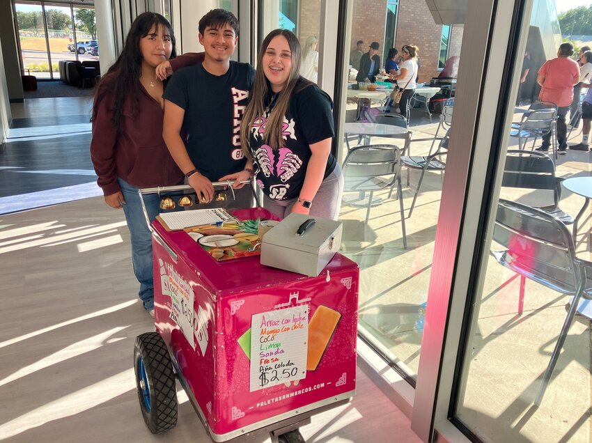 Neyla Hernandez, 16, (on left), Erik Vergara, 15, and Kaysie Rodriguez, 16, sell paletas to raise money for Early College High School. The carts ring as they move, and teachers say it is a common sound during the school day.