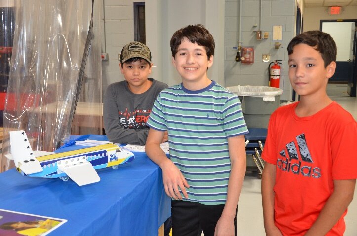 Students in Mr. Dan Krotzer's Invention & Innovation class at Metz Middle School in Manassas City show off a model airplane they made through the Build It Better Program that simulates real day-to-day working conditions for inventors and engineers.